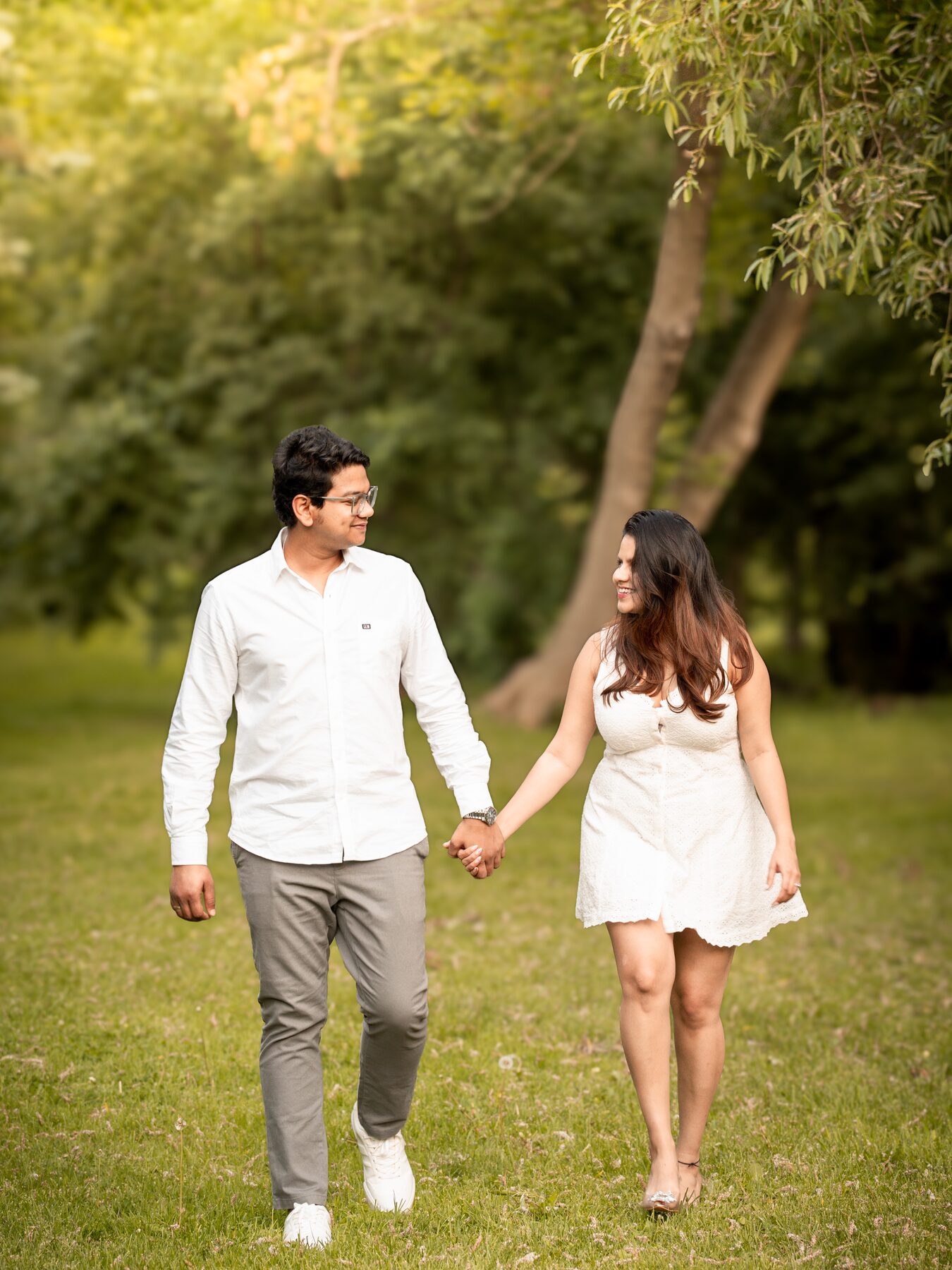 Couple walking hand in hand under trees